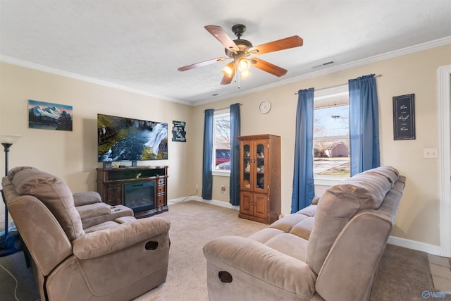 living area featuring ornamental molding, a glass covered fireplace, visible vents, and baseboards