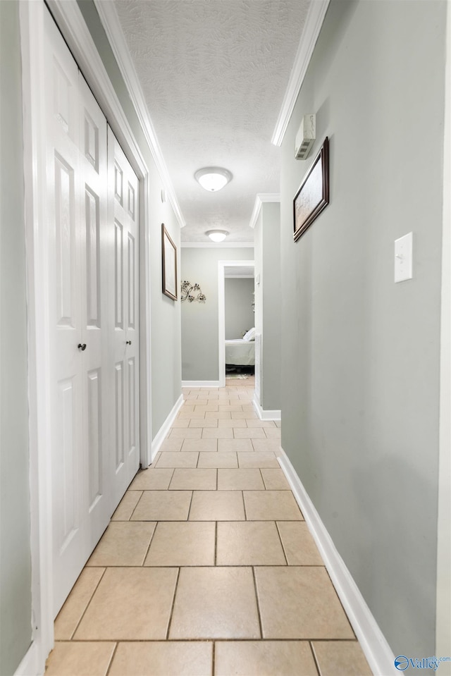 hall with light tile patterned flooring, crown molding, a textured ceiling, and baseboards