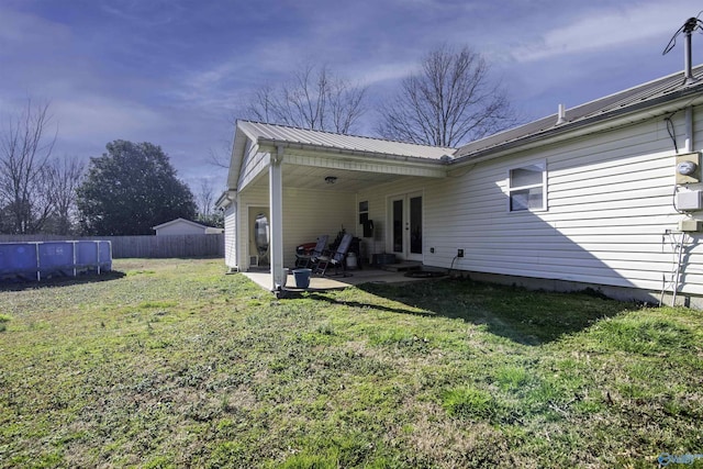 back of property with french doors, a patio, metal roof, fence, and a yard