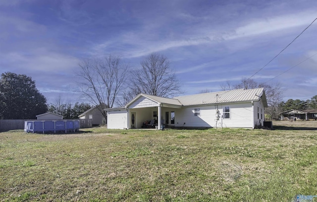 back of house with metal roof, a yard, and fence