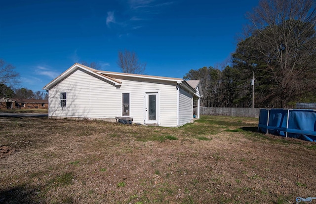 back of house with a yard, fence, and a swimming pool