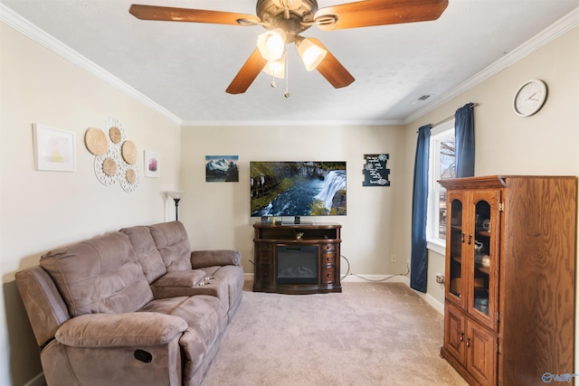 living room featuring crown molding, light colored carpet, a glass covered fireplace, ceiling fan, and baseboards