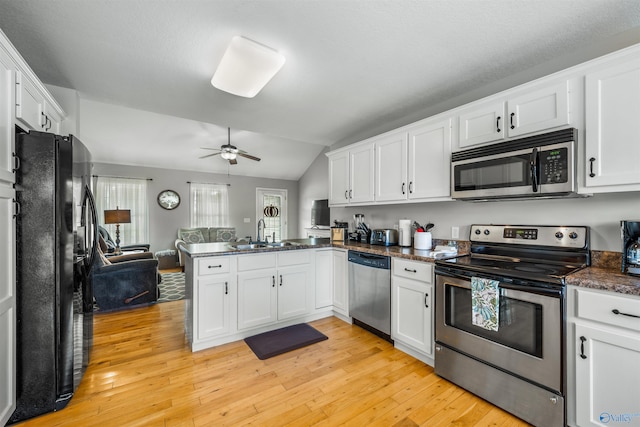 kitchen with stainless steel appliances, lofted ceiling, kitchen peninsula, and white cabinets