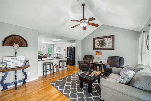 living room featuring ceiling fan with notable chandelier, lofted ceiling, and light hardwood / wood-style flooring