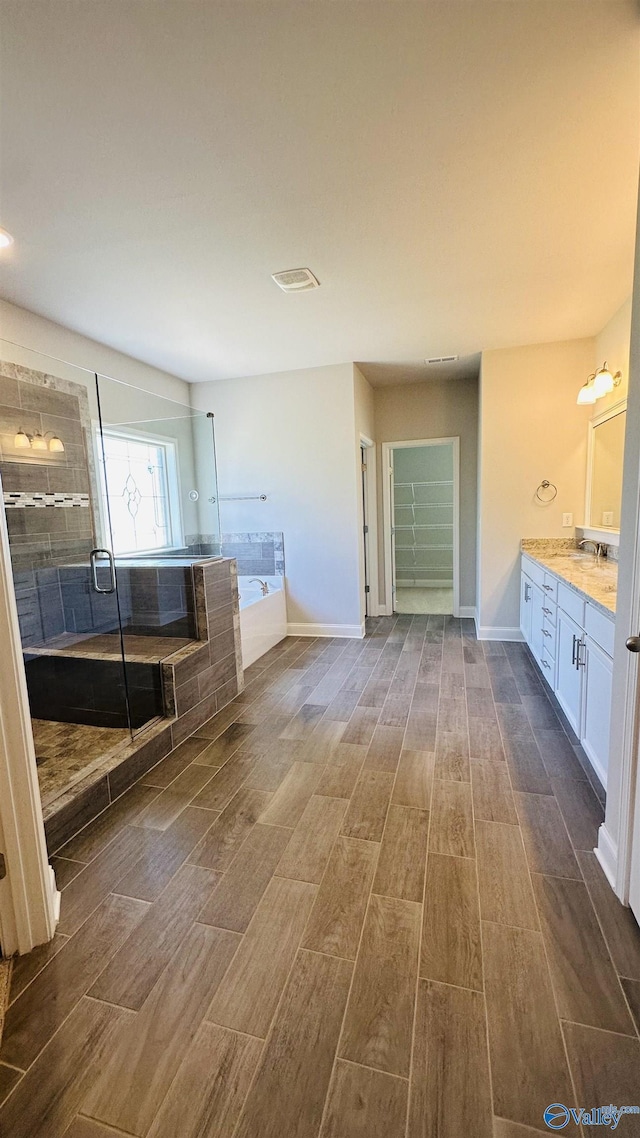 bathroom with wood finished floors, a stall shower, a garden tub, and vanity