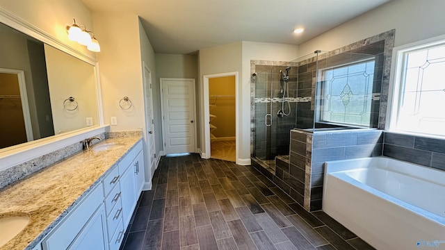 full bath featuring a stall shower, vanity, wood tiled floors, a bath, and a walk in closet