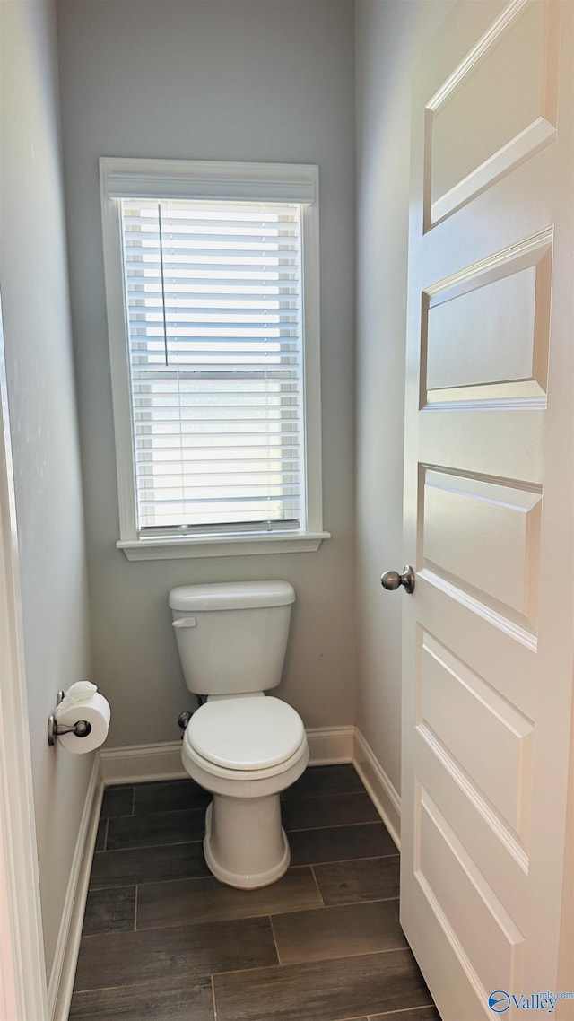 bathroom with toilet, baseboards, and wood finished floors