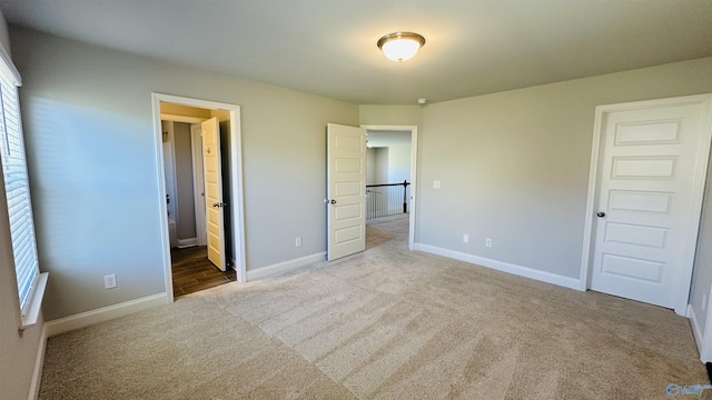 unfurnished bedroom featuring carpet flooring, baseboards, multiple windows, and ensuite bathroom