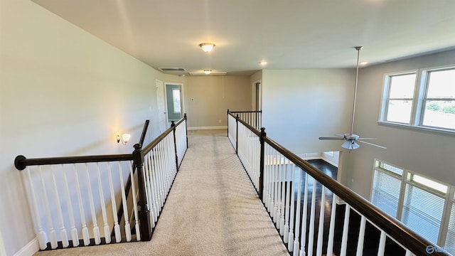 hall with an upstairs landing, baseboards, light carpet, and attic access