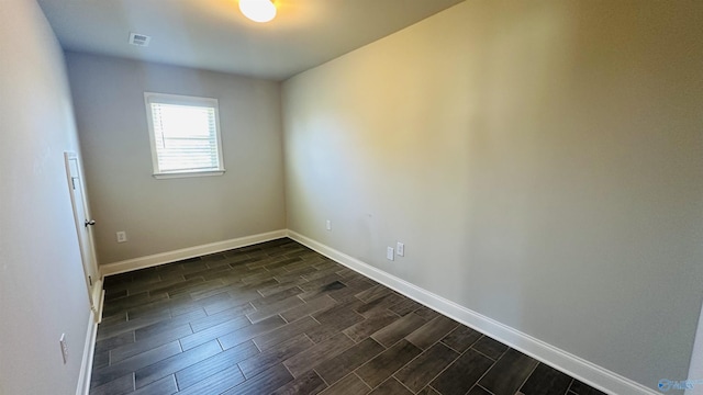 empty room featuring dark wood-type flooring and baseboards