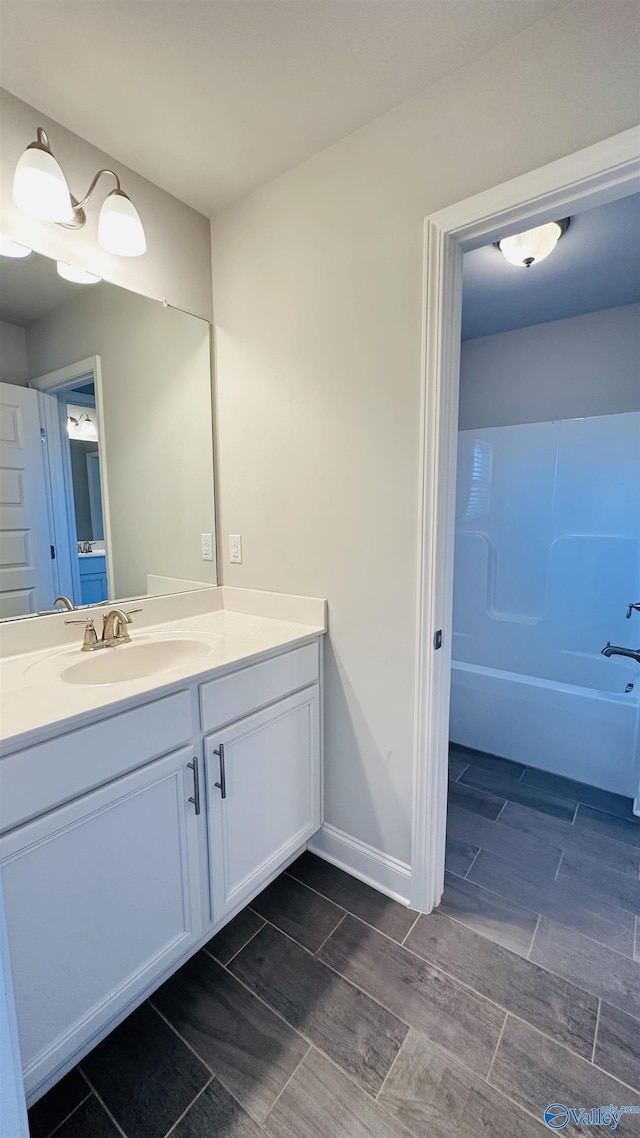 bathroom with vanity, wood finish floors, and baseboards
