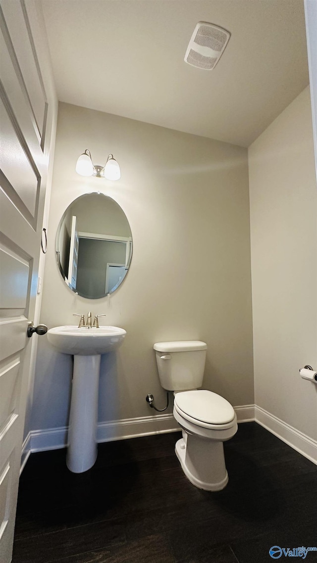 half bath featuring baseboards, toilet, and wood finished floors