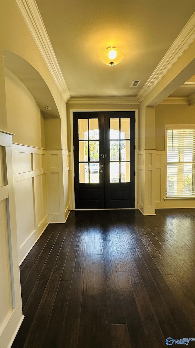 doorway featuring a decorative wall, french doors, crown molding, dark wood-style flooring, and wainscoting