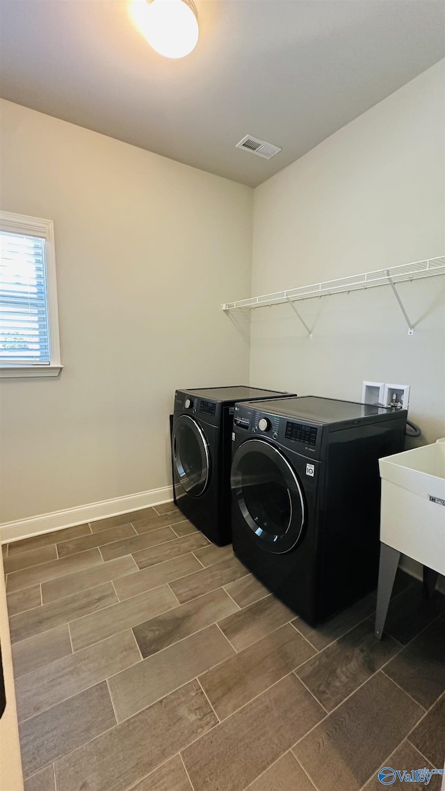 clothes washing area with independent washer and dryer, wood finish floors, and baseboards