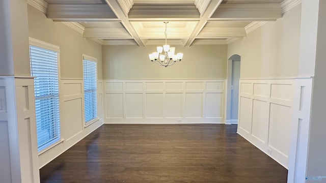unfurnished dining area featuring a decorative wall, a chandelier, dark wood-style flooring, beamed ceiling, and coffered ceiling