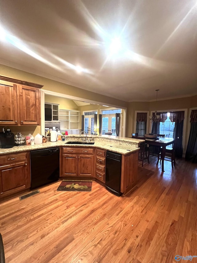 kitchen featuring black dishwasher, sink, light hardwood / wood-style floors, kitchen peninsula, and light stone countertops