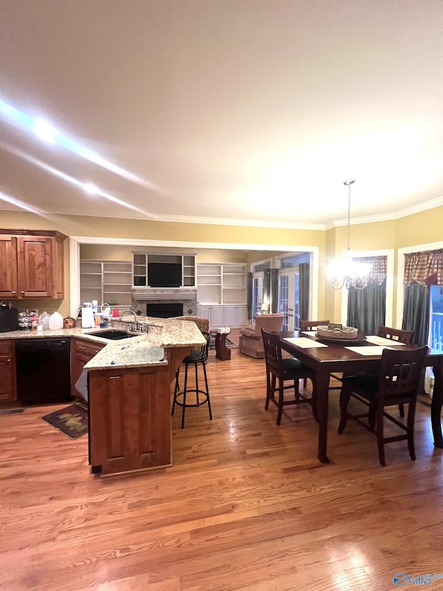 kitchen featuring pendant lighting, sink, black dishwasher, a kitchen bar, and light wood-type flooring