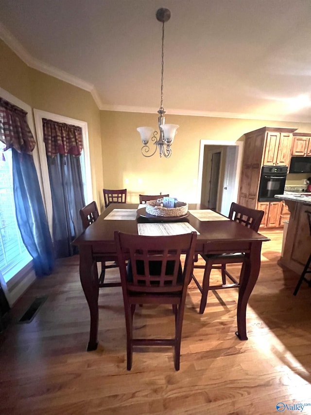 dining space with crown molding, light hardwood / wood-style floors, and a chandelier