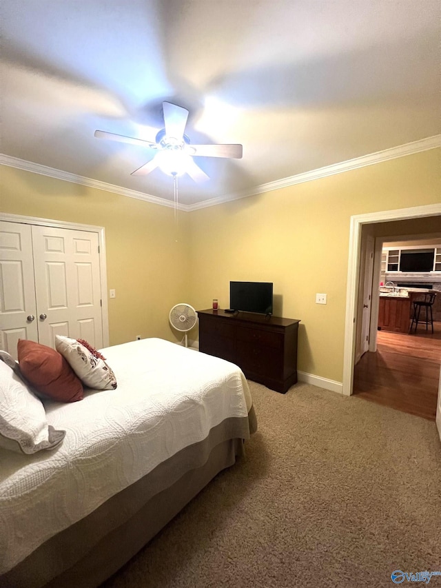 carpeted bedroom with ceiling fan, ornamental molding, and a closet