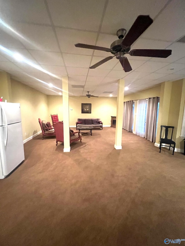 basement with ceiling fan, carpet, white fridge, and a drop ceiling