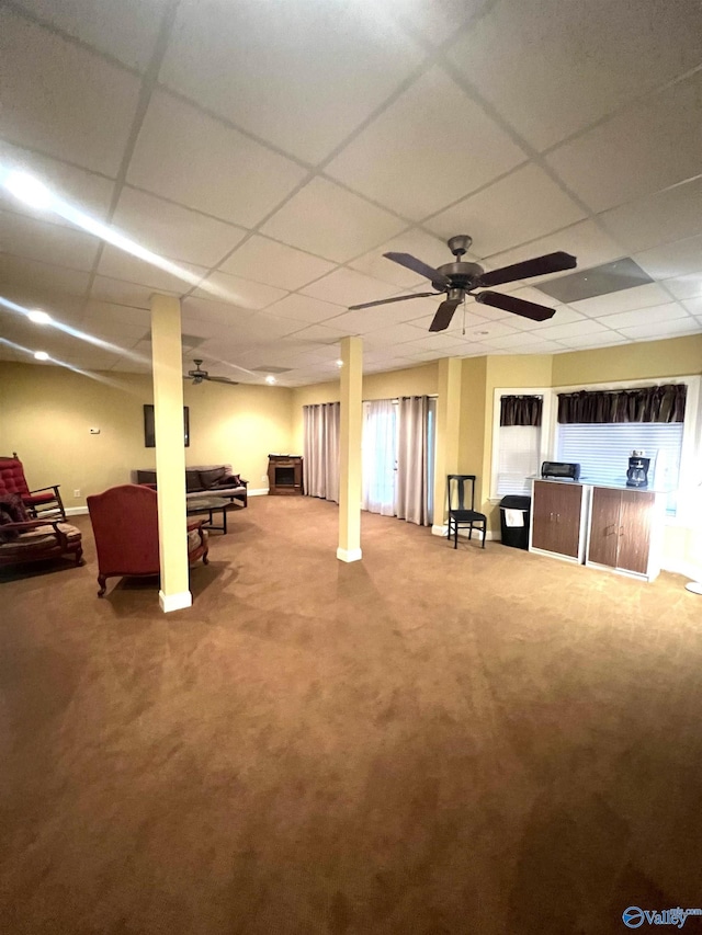 basement featuring carpet flooring, a drop ceiling, and ceiling fan