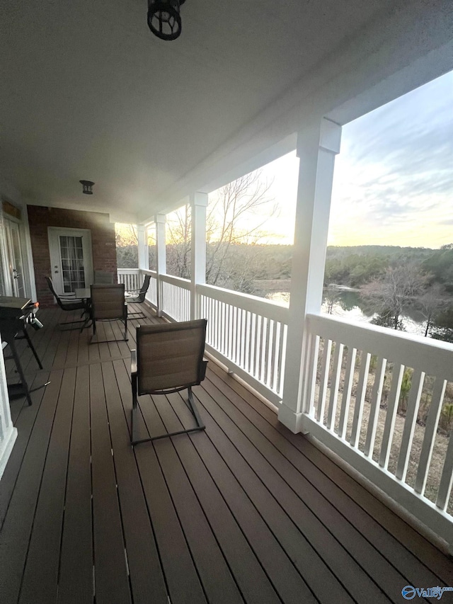 deck at dusk featuring a water view