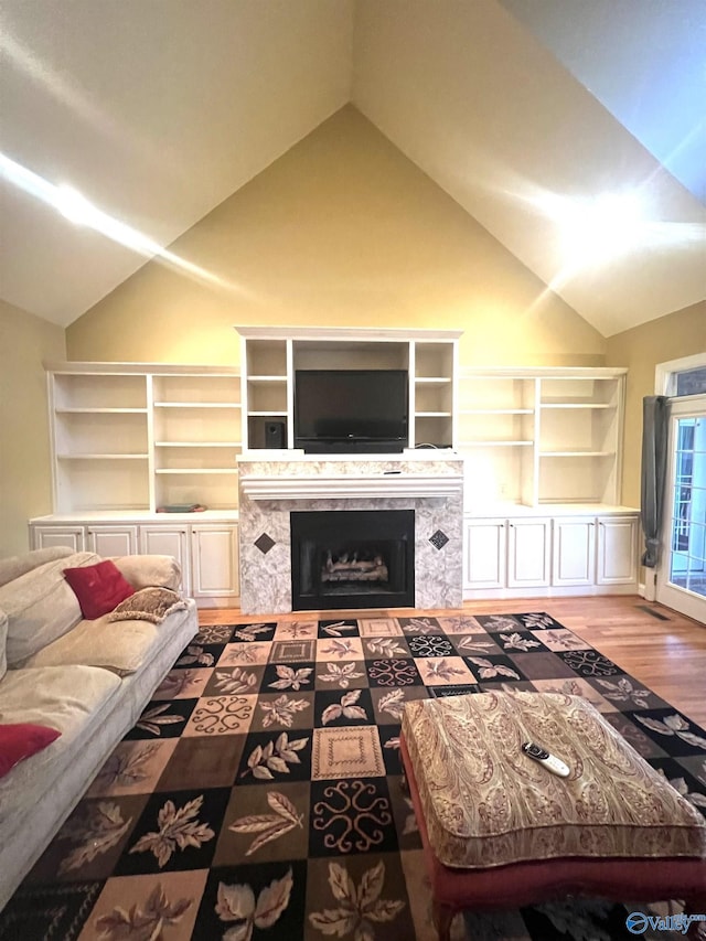 living room featuring lofted ceiling, a fireplace, and wood-type flooring