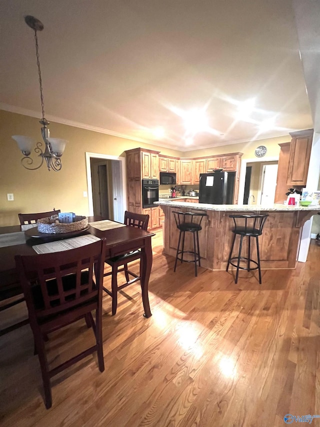 dining space featuring a notable chandelier, ornamental molding, and light wood-type flooring