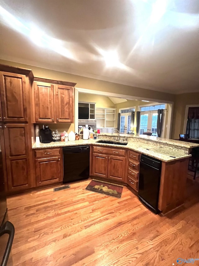 kitchen featuring light stone counters, sink, black dishwasher, and light wood-type flooring