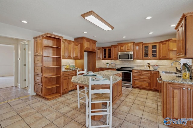 kitchen featuring a kitchen breakfast bar, light stone countertops, light tile patterned floors, a kitchen island, and stainless steel appliances