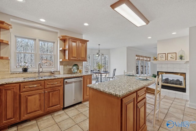 kitchen with dishwasher, a center island, sink, decorative light fixtures, and a fireplace