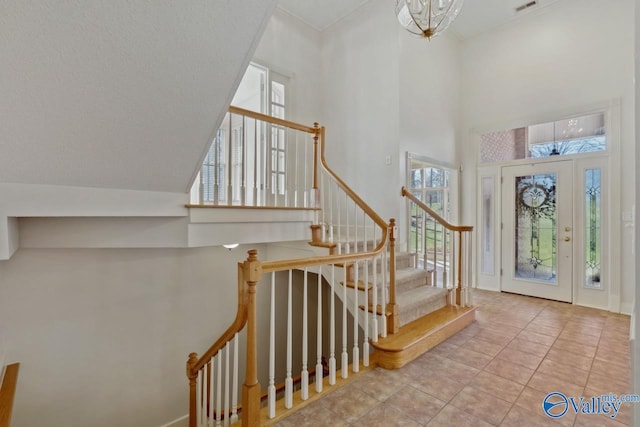 tiled foyer entrance with a towering ceiling and a notable chandelier