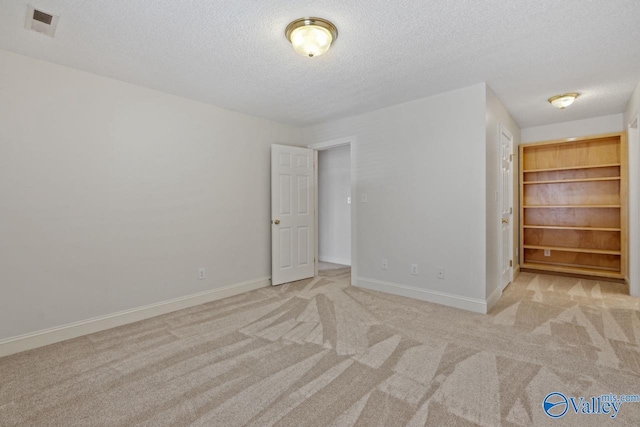 unfurnished bedroom featuring light colored carpet, a textured ceiling, and a closet