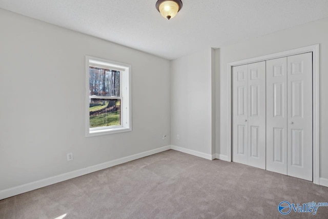 unfurnished bedroom with a closet, light colored carpet, and a textured ceiling