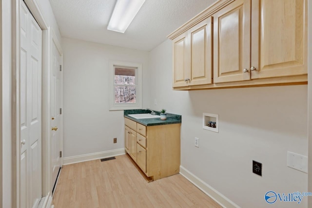 washroom featuring cabinets, sink, washer hookup, hookup for an electric dryer, and light hardwood / wood-style floors