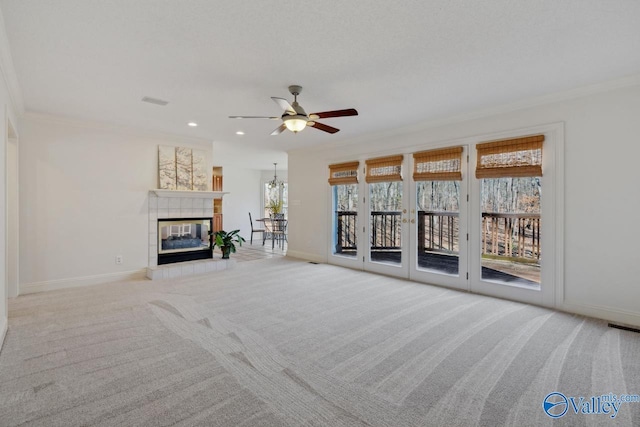 unfurnished living room with light colored carpet, ceiling fan, crown molding, and a tiled fireplace