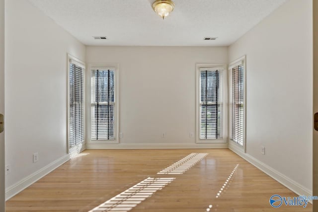 unfurnished room with a textured ceiling and light hardwood / wood-style flooring