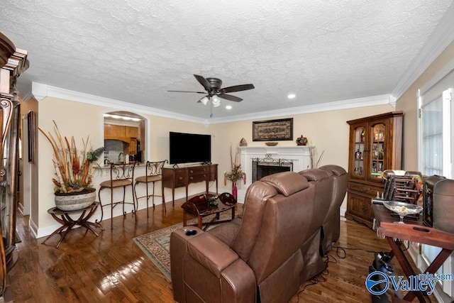 living room with ornamental molding, dark hardwood / wood-style floors, a textured ceiling, and ceiling fan