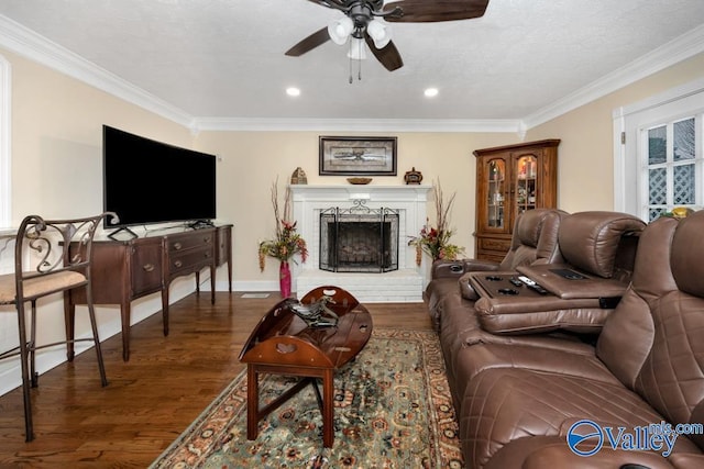 living room featuring crown molding, ceiling fan, a fireplace, and dark hardwood / wood-style flooring