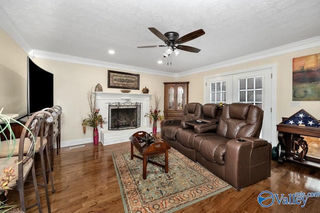 living room with dark wood-type flooring, ornamental molding, a textured ceiling, a brick fireplace, and french doors