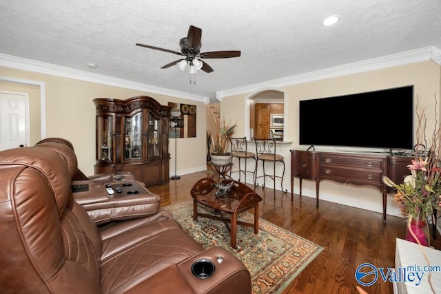 living room with dark hardwood / wood-style flooring, ceiling fan, ornamental molding, and a textured ceiling