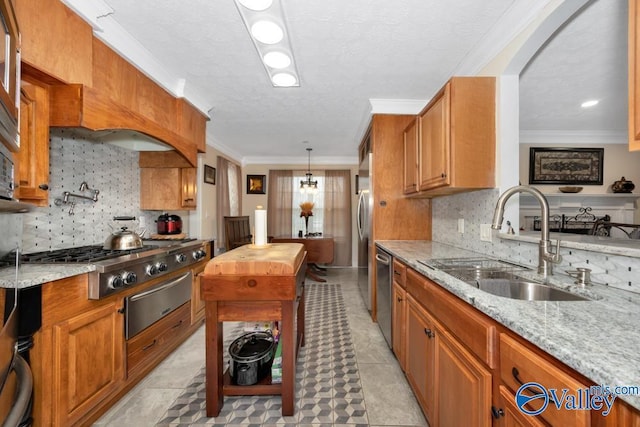 kitchen with appliances with stainless steel finishes, pendant lighting, butcher block countertops, sink, and crown molding