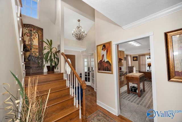 staircase with a high ceiling, ornamental molding, hardwood / wood-style flooring, and a notable chandelier