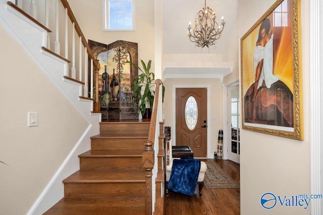 foyer with a high ceiling, wood-type flooring, and an inviting chandelier