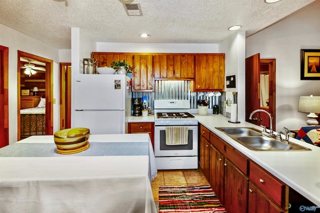 kitchen with light tile patterned flooring, white appliances, a textured ceiling, ceiling fan, and sink