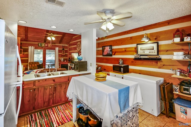 kitchen featuring a textured ceiling, stainless steel refrigerator, and ceiling fan