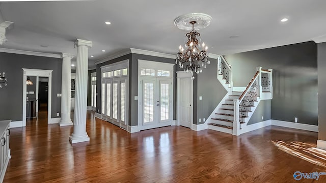 entryway featuring ornamental molding, dark wood-type flooring, ornate columns, and a chandelier