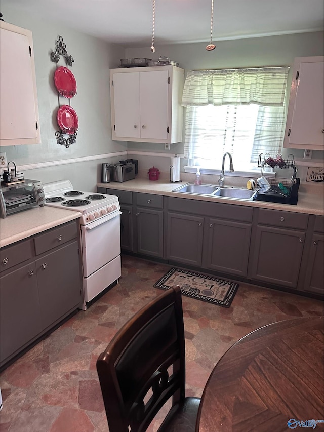 kitchen with gray cabinetry, light countertops, white electric range oven, and a sink