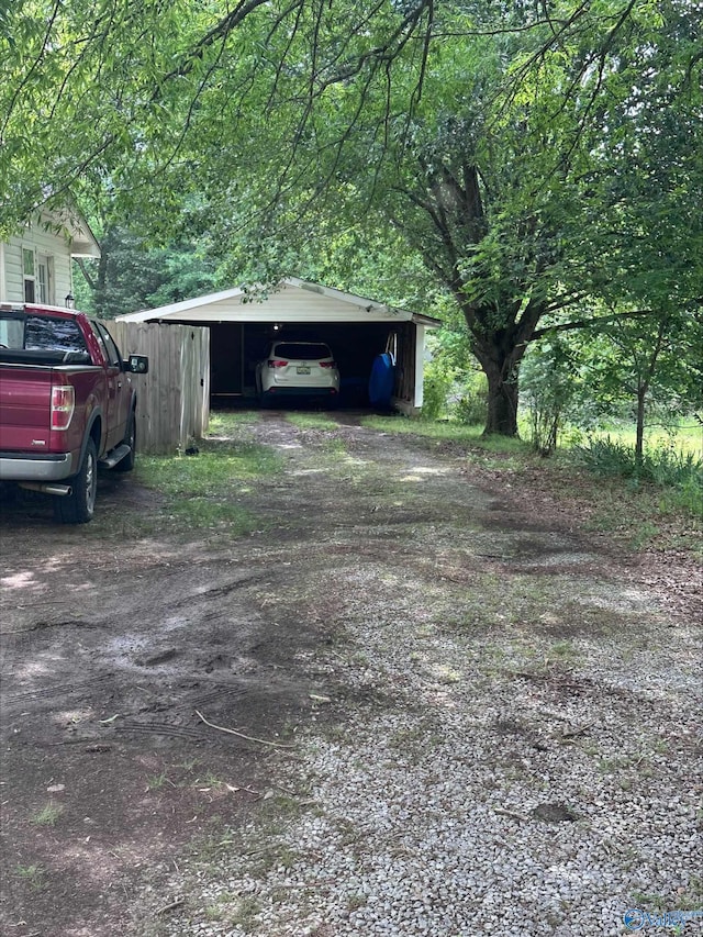 garage featuring a detached carport and dirt driveway