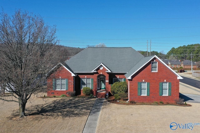 view of front facade with brick siding and a shingled roof